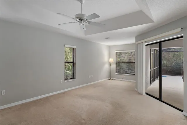 an empty room with chandelier fan and windows