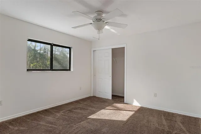 an empty room with a ceiling fan and a window