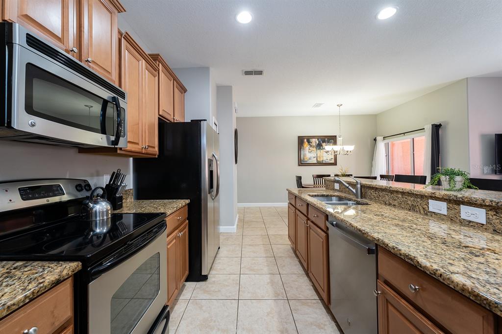 8957 Cat Palm Road Kissimmee, FL 34747 - Photo 11 of 25 a kitchen with stainless steel appliances granite countertop a stove refrigerator and microwave