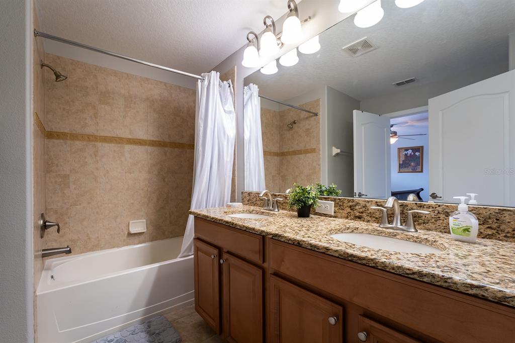 8957 Cat Palm Road Kissimmee, FL 34747 - Photo 19 of 25 a bathroom with a granite countertop sink a large mirror and a bathtub with shower