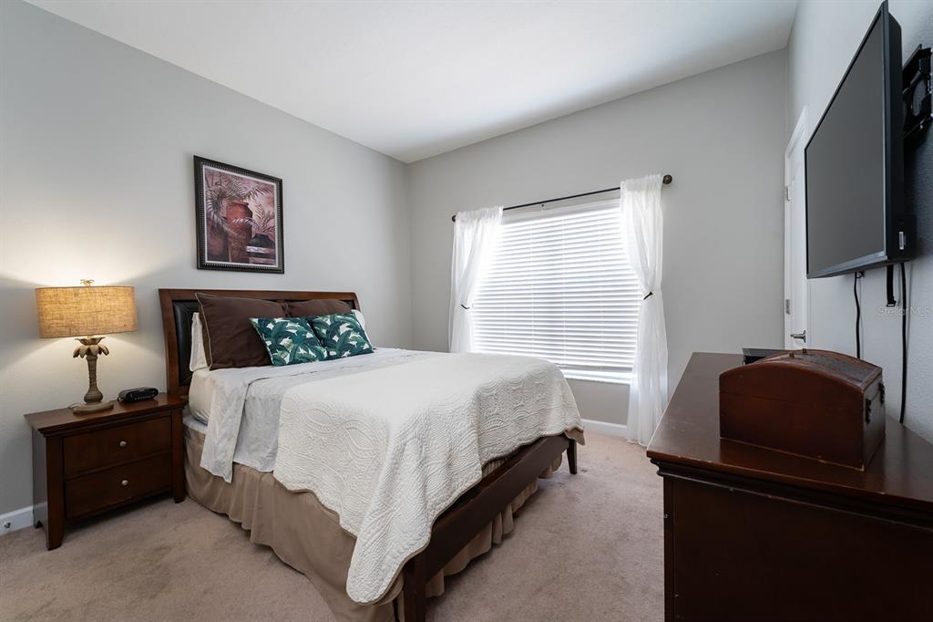 8957 Cat Palm Road Kissimmee, FL 34747 - Photo 3 of 25 a bedroom with a bed and a flat tv screen on a dresser