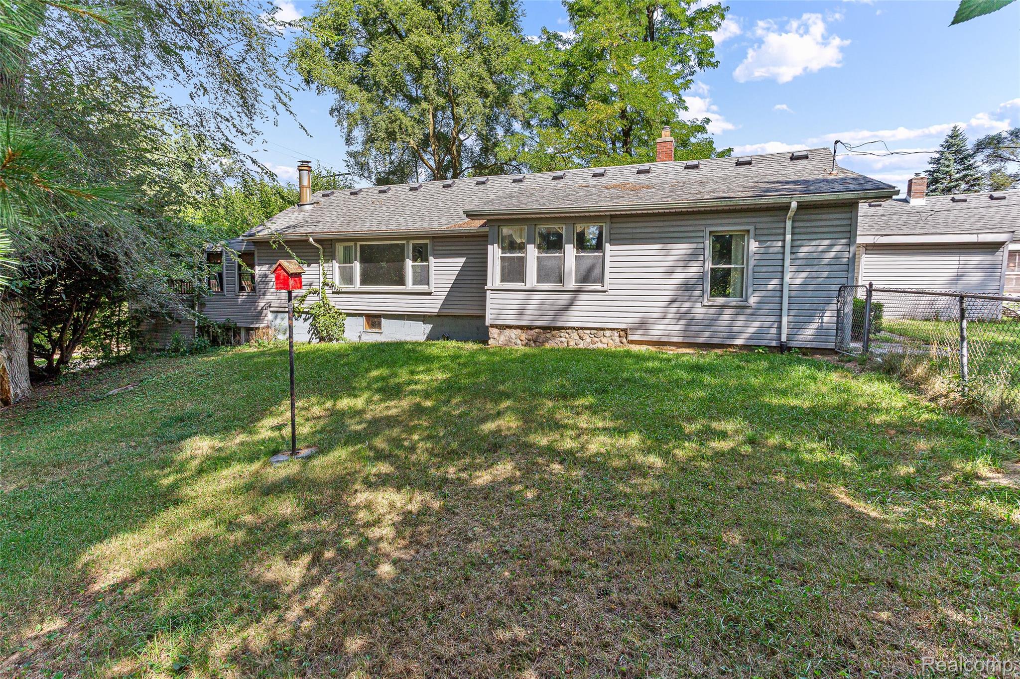 2550 Loon Lake Road Wixom, MI 48393 - Photo 3 of 36 Expansive lawn with mature trees and a chain-link fence