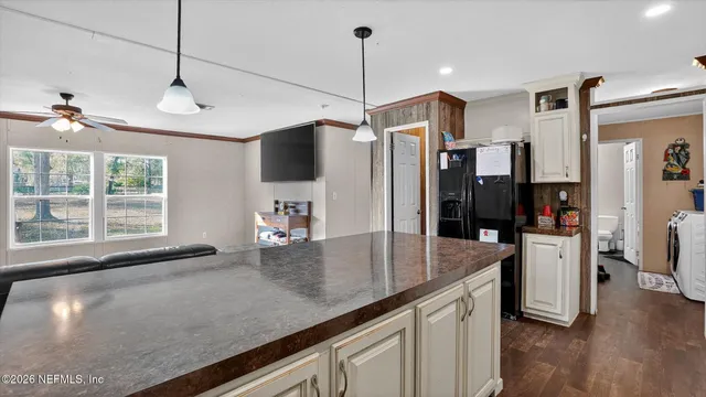 a kitchen with stainless steel appliances granite countertop a sink a refrigerator a stove a dining table and chairs with wooden floor