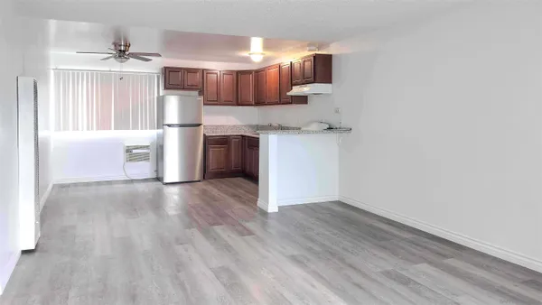 a view of kitchen and empty room with wooden floor