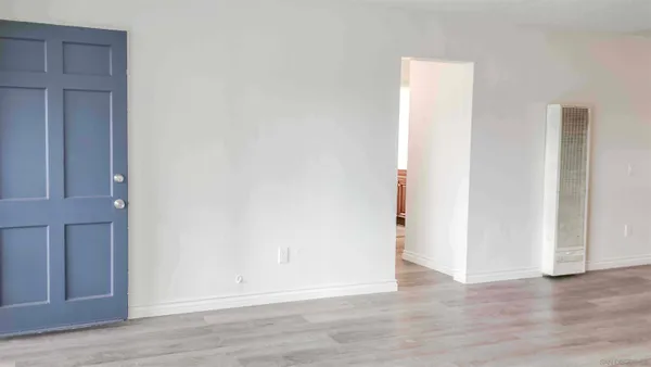 a view of an empty room with wooden floor and closet