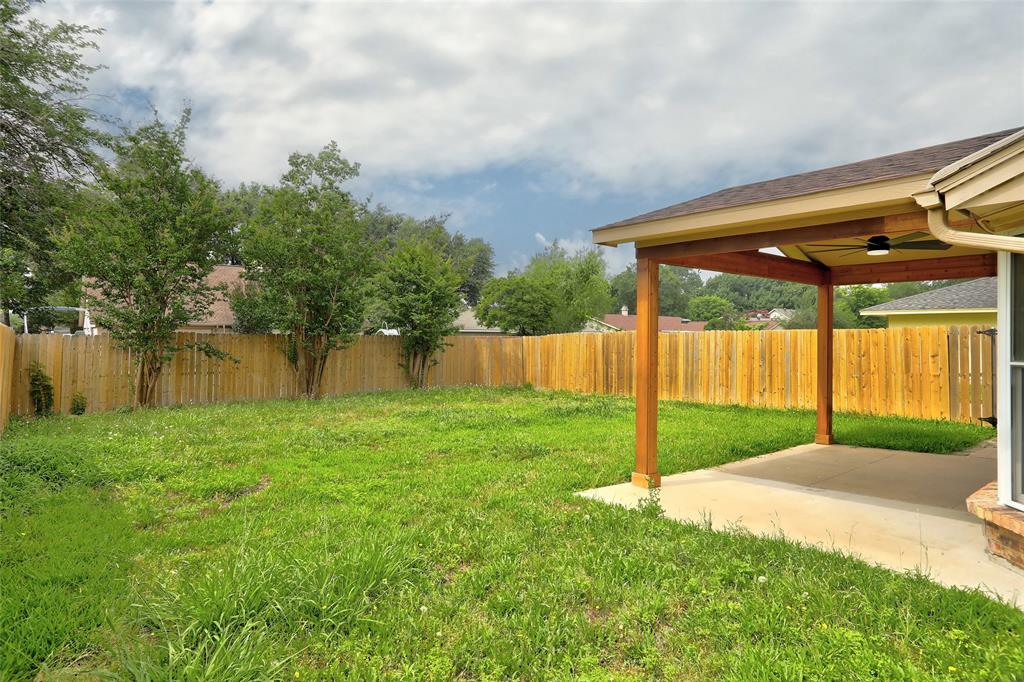 2102 Apollo Road Richardson, TX 75081 - Photo 25 of 26 Expansive backyard featuring a covered patio with a ceiling fan, a full privacy fence, and mature trees along the perimeter