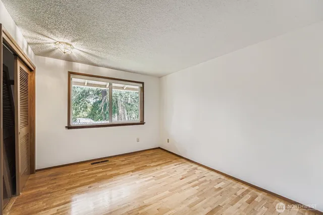 an empty room with wooden floor and window