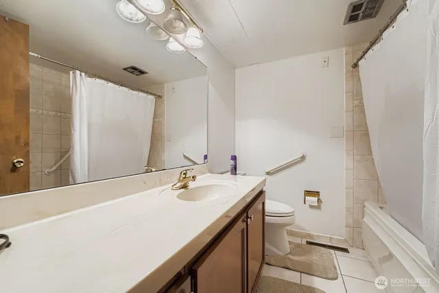 a bathroom with a sink a toilet a mirror and shower