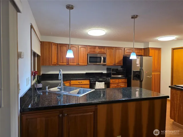 a kitchen with stainless steel appliances granite countertop a sink refrigerator and cabinets