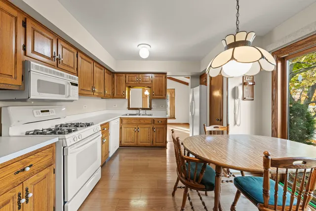 a kitchen with stainless steel appliances granite countertop a stove a sink dishwasher a dining table and chairs with wooden floor