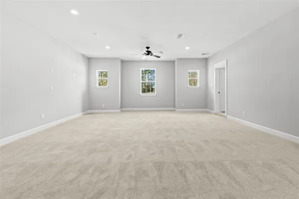 an empty room with windows and chandelier fan