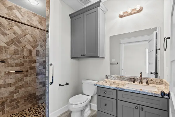 a bathroom with a granite countertop sink a toilet and a mirror