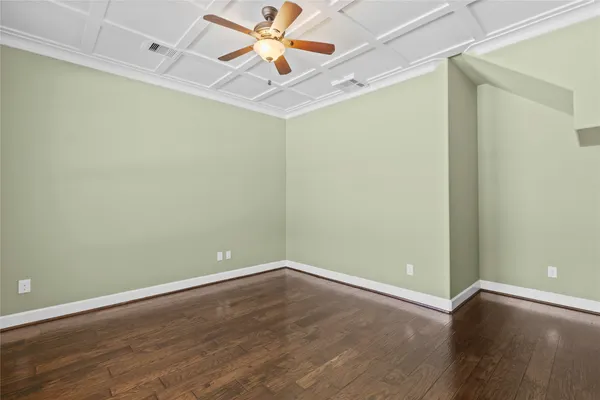 an empty room with wooden floor and fan