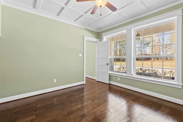 an empty room with wooden floor and windows with curtains