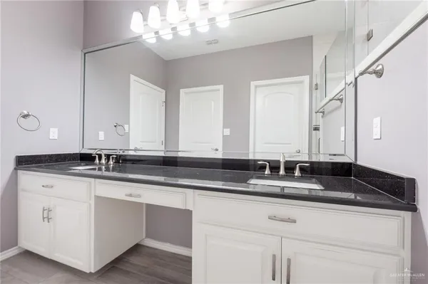 a bathroom with a granite countertop double vanity and a mirror