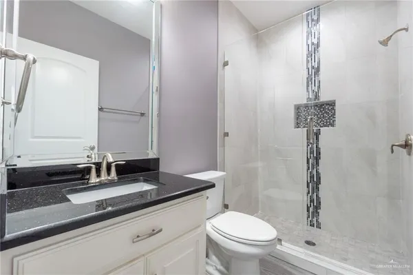 a bathroom with a granite countertop sink a toilet and a mirror