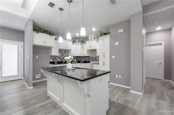 a kitchen with kitchen island granite countertop a sink cabinets and stainless steel appliances
