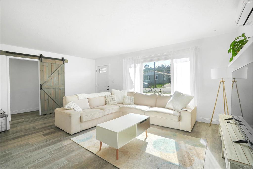 a living room with furniture white walls and a large window