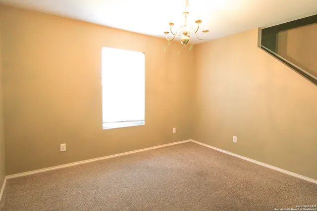 an empty room with a chandelier fan and windows