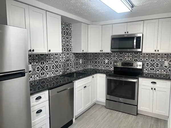a kitchen with white cabinets stainless steel appliances and sink