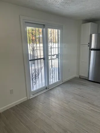 a view of an empty room with a window and wooden floor