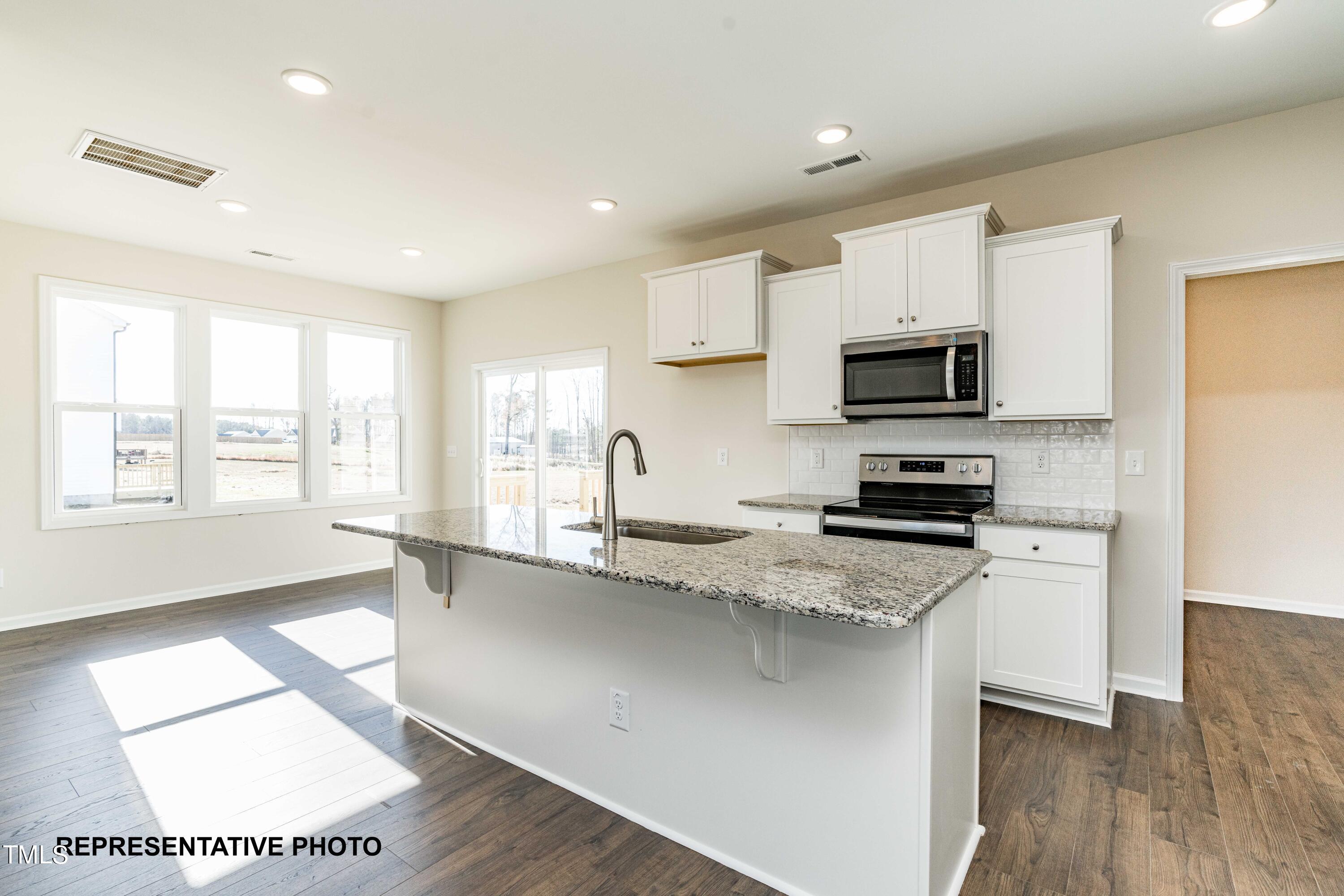 112 Springtooth Drive Zebulon, NC 27597 - Photo 2 of 10 a kitchen with stainless steel appliances granite countertop a sink a stove a microwave a center island and cabinets