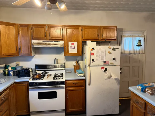 a white refrigerator freezer sitting inside of a kitchen with stainless steel appliances granite countertop a refrigerator stove and microwave