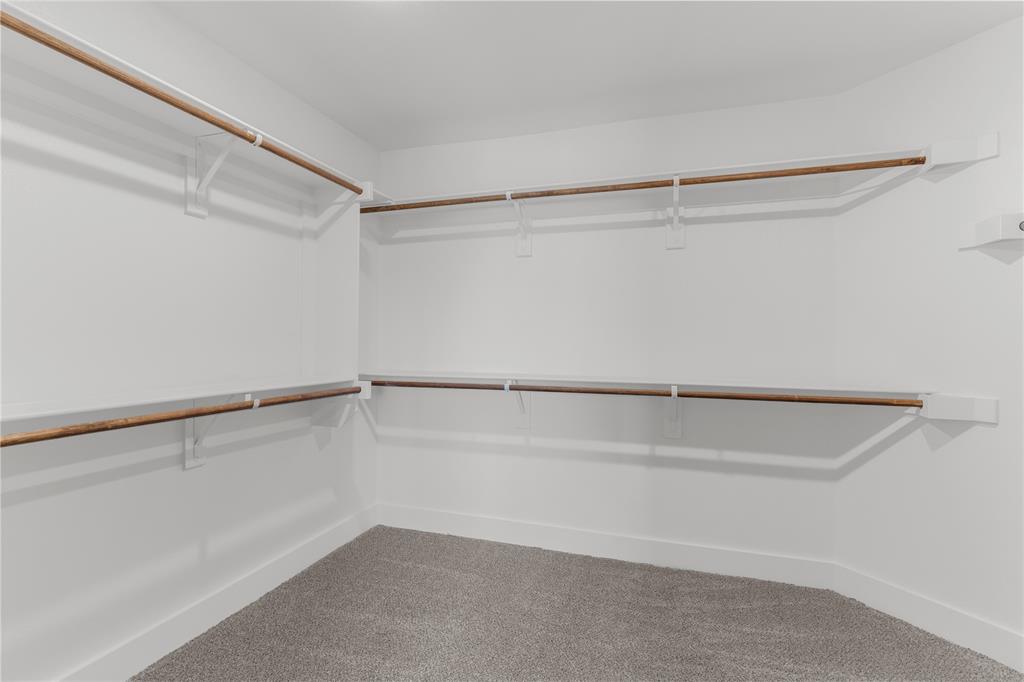 1650 Palladio Loop, Unit 2 Princeton, TX 75407 - Photo 7 of 14 Spacious walk-in closet featuring white walls, crisp white trim, multiple wood-finish hanging rods, and plush gray carpeting