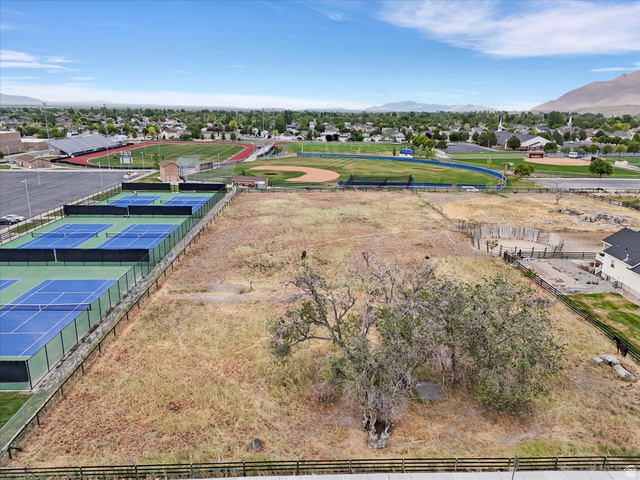 149 Bates Canyon Road Stansbury Park, UT 84074 - Photo 7 of 9 Expansive undeveloped land parcel featuring mature trees, a perimeter fence, and mountain scenery