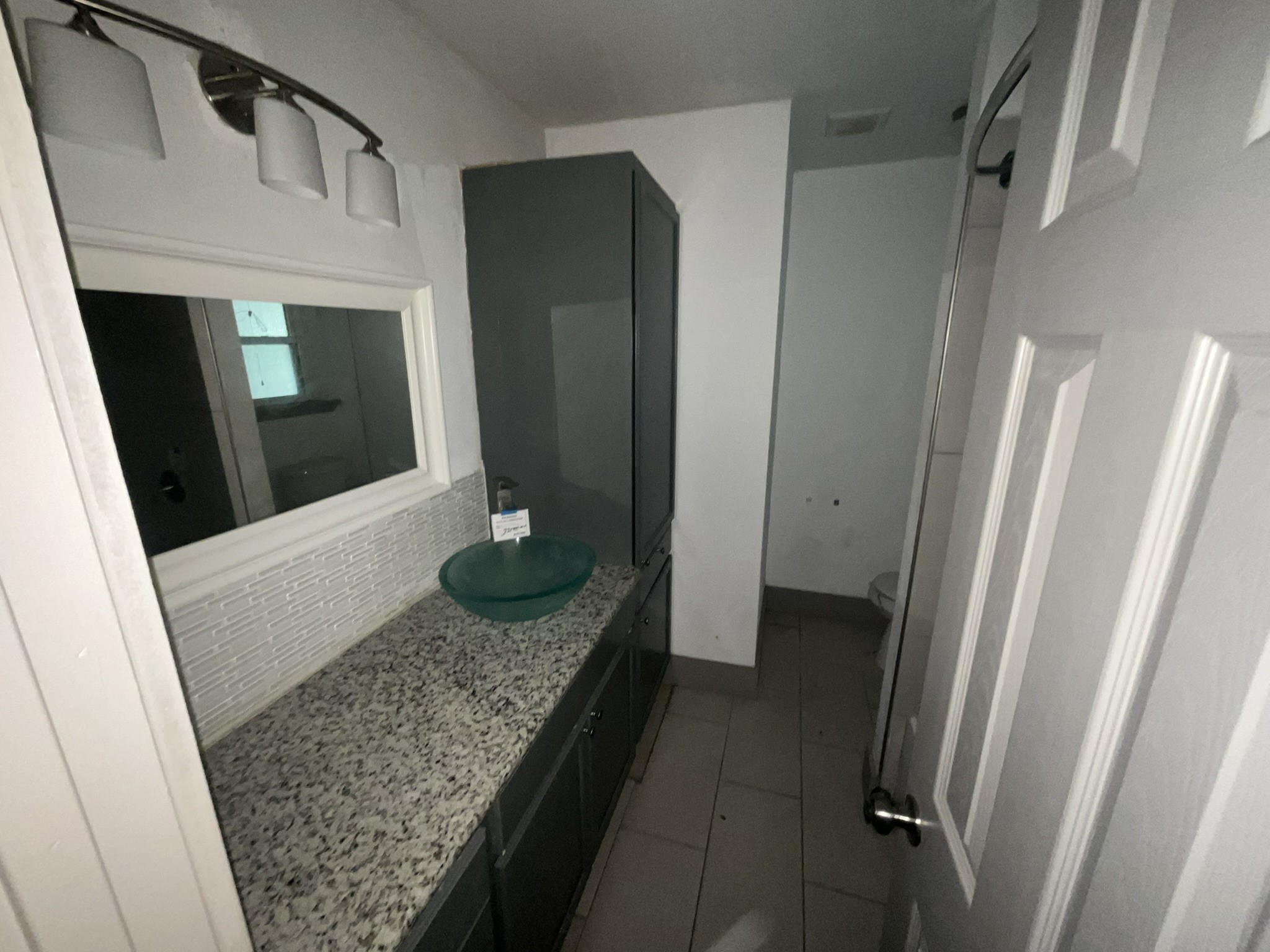 2314 Creekleaf Road Houston, TX 77068 - Photo 12 of 12 Modern bathroom featuring a sleek granite countertop with a stylish glass vessel sink and ample cabinet storage.