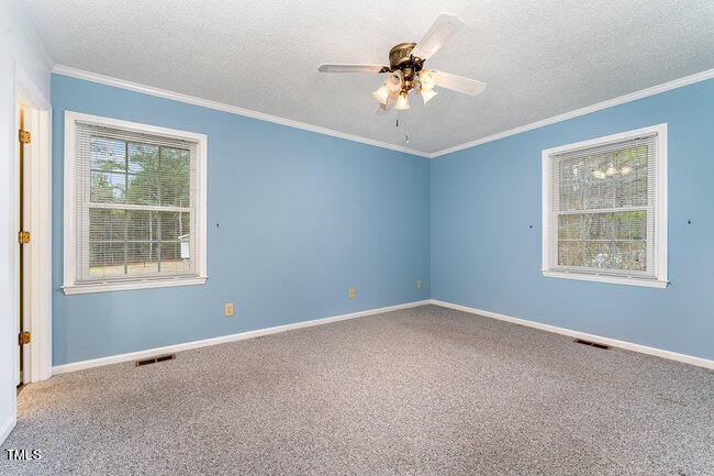 6693 Silk Hope Liberty Road Siler City, NC 27344 - Photo 14 of 32 an empty room with windows and chandelier fan