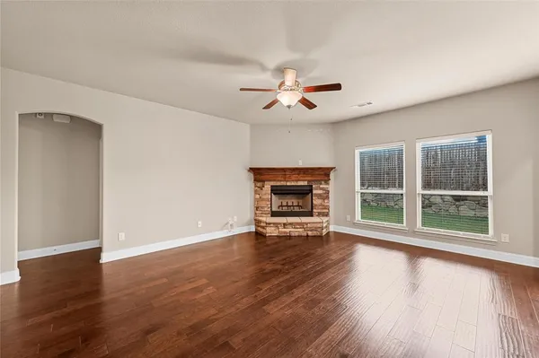 a view of an empty room with a window and wooden floor