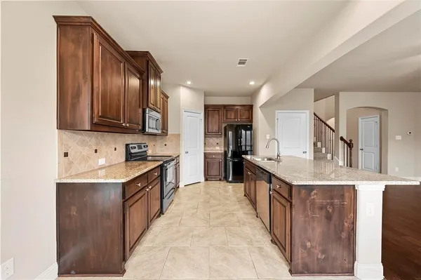 a kitchen with stainless steel appliances granite countertop a sink stove top oven and cabinets