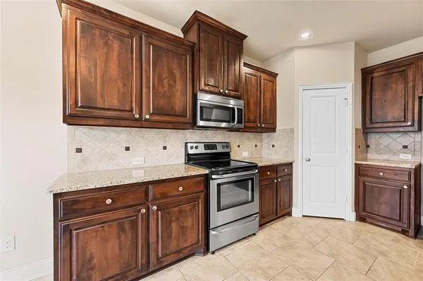 a kitchen with granite countertop wooden cabinets stainless steel appliances and a sink