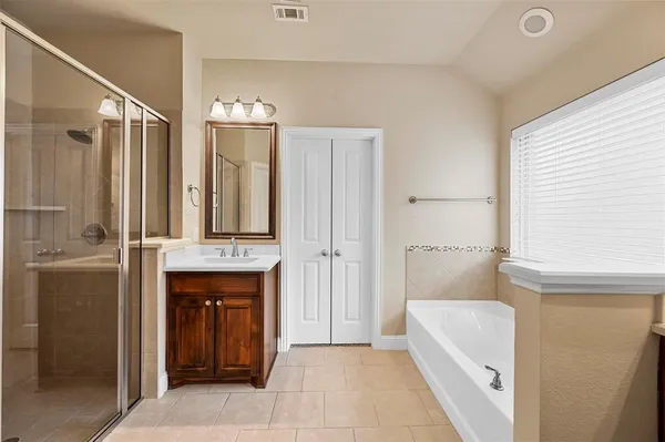 a bathroom with a tub sink shower and mirror