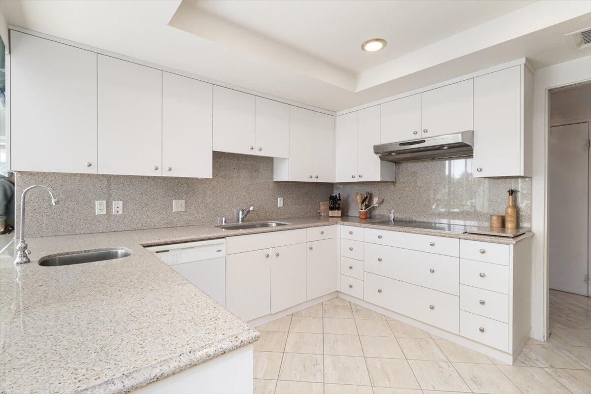 900 Island Drive, Unit 313 Rancho Mirage, CA 92270 - Photo 5 of 62 a kitchen with granite countertop white cabinets and stainless steel appliances