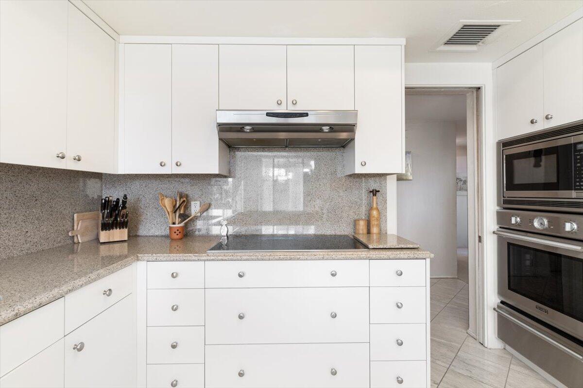 900 Island Drive, Unit 313 Rancho Mirage, CA 92270 - Photo 6 of 62 a kitchen with granite countertop white cabinets and stainless steel appliances