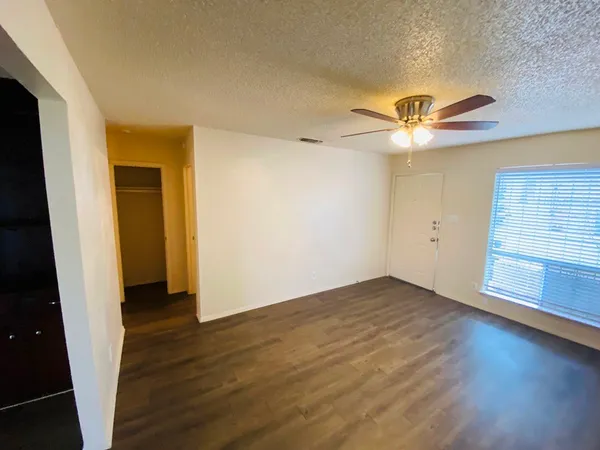 an empty room with wooden floor and chandelier fan