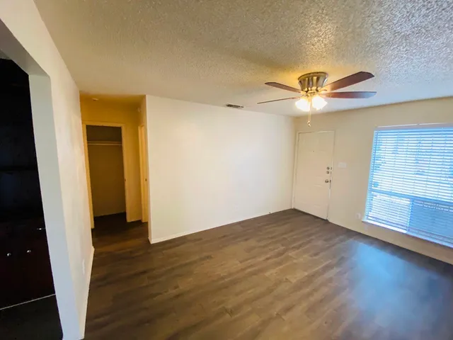an empty room with wooden floor and chandelier fan