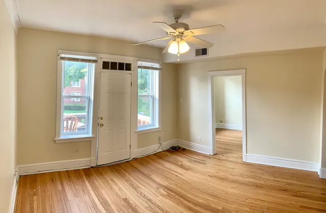 an empty room with wooden floor and windows