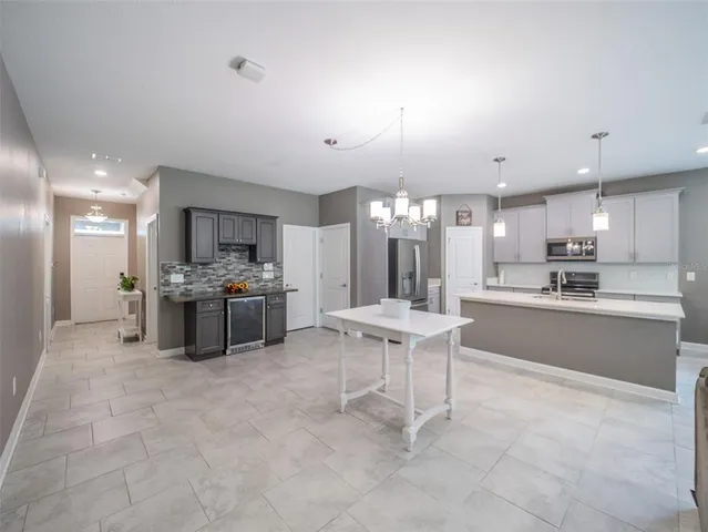 a large kitchen with kitchen island a large counter top stainless steel appliances and cabinets