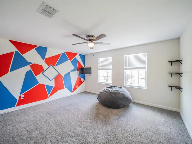 an empty room with a ceiling fan and carpet