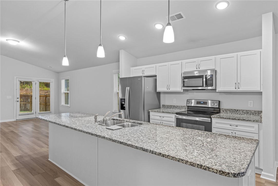 24 Chalet Court Anderson, SC 29621 - Photo 9 of 39 This kitchen features a spacious island, modern appliances, and convenient access to the outdoor area.