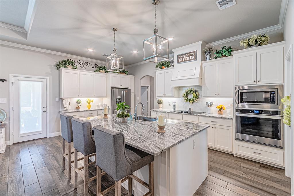 1009 Henry Way Springtown, TX 76082 - Photo 11 of 40 Kitchen featuring tasteful backsplash, arched walkways, appliances with stainless steel finishes, a breakfast bar area, and white cabinetry