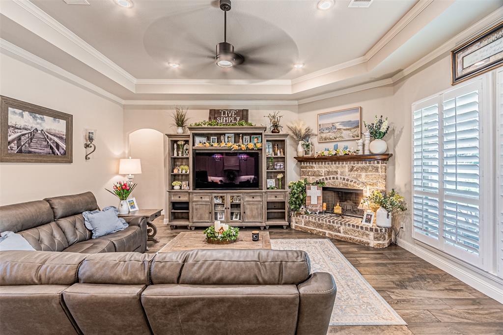 1009 Henry Way Springtown, TX 76082 - Photo 12 of 40 Living room featuring arched walkways, wood finished floors, ceiling fan, a tray ceiling, and crown molding