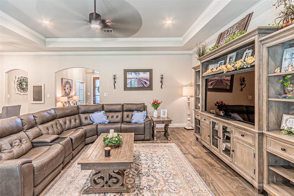 1009 Henry Way Springtown, TX 76082 - Photo 14 of 40 Living room featuring arched walkways, light wood-type flooring, a raised ceiling, ceiling fan, and ornamental molding