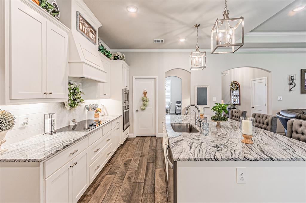 1009 Henry Way Springtown, TX 76082 - Photo 16 of 40 Kitchen with white cabinets, arched walkways, recessed lighting, light stone countertops, and decorative light fixtures