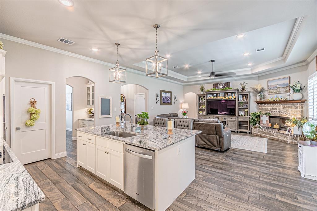 1009 Henry Way Springtown, TX 76082 - Photo 17 of 40 Kitchen with white cabinetry, arched walkways, dishwasher, light stone counters, and a center island with sink