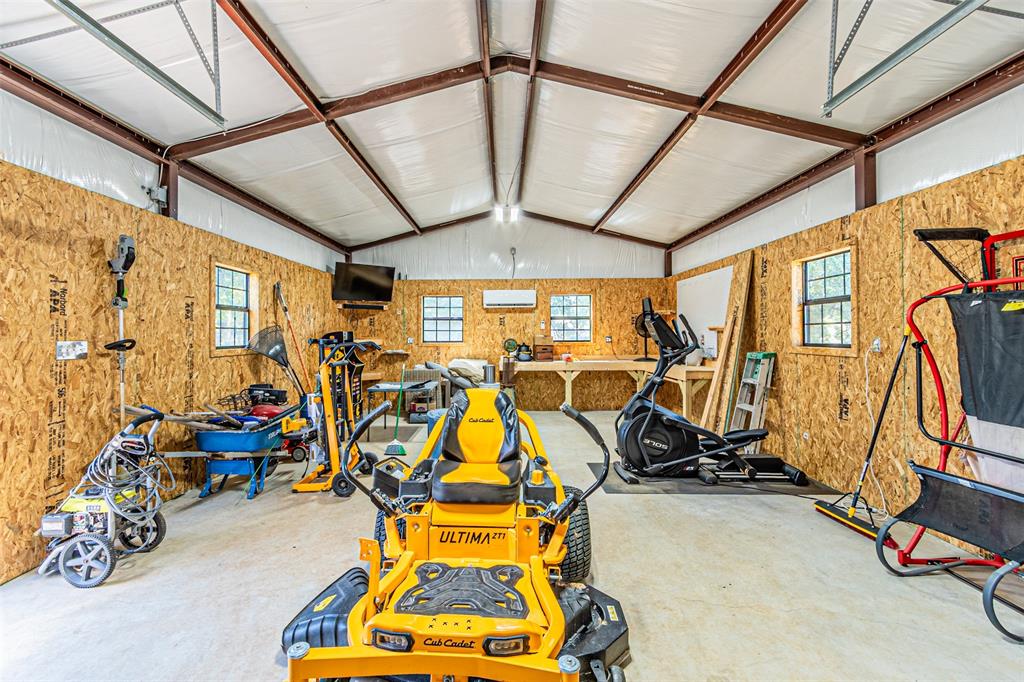 1009 Henry Way Springtown, TX 76082 - Photo 34 of 40 Workout room with a garage, healthy amount of natural light, lofted ceiling, a wall unit AC, and wooden walls