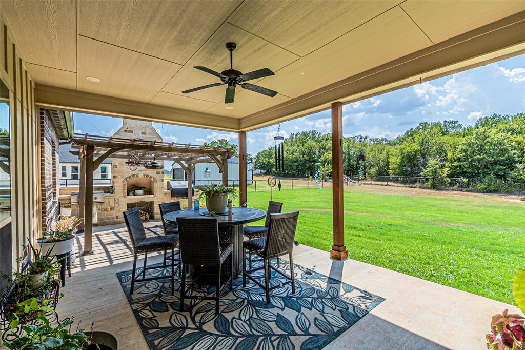 1009 Henry Way Springtown, TX 76082 - Photo 35 of 40 Fenced backyard featuring a patio area, an outdoor stone fireplace, outdoor dining area, and ceiling fan